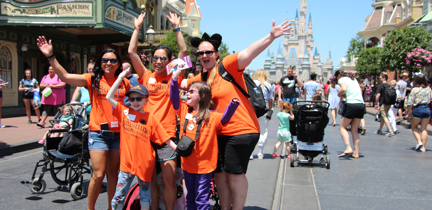 Taylor and volunteers wave in front of Disney castle