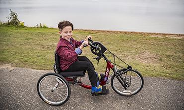 boy on adapted bike riding along a lakeside trail