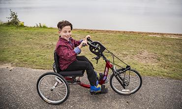 boy on adapted bike riding along a lakeside trail
