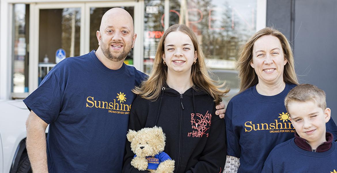 Dad, mom, and brother surround young teenage girl wearing Motley Crue sweater outside of a store