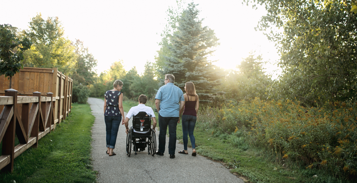 Family walks away from camera on a paved pathway in the fall during sunset
