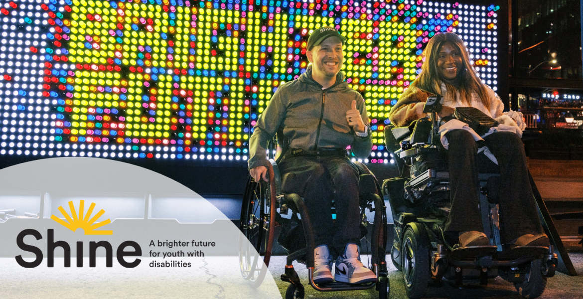 Marco is seated in a wheelchair wearing a black shine cap beside Taylor in a power wheelchair both are in front of a giant lite-brite board that spells brighter futures