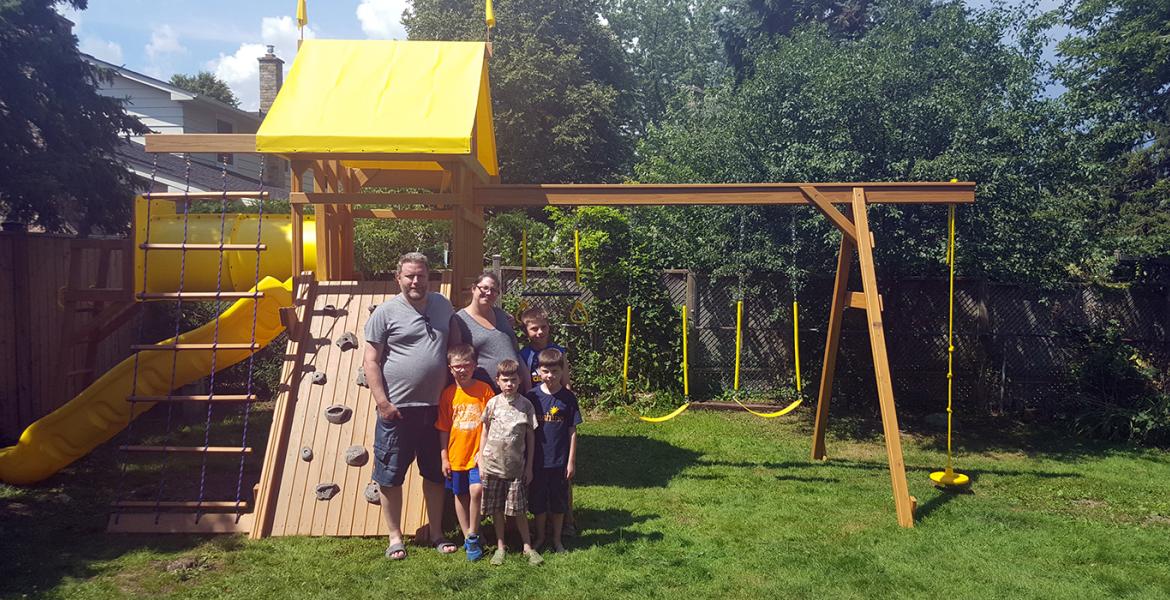 Daithi and family gather in their backyard in front of new playground equipment