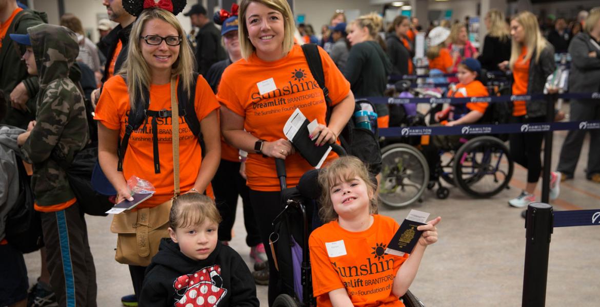 Group of Sunshine DreamLift participants in bright orange shirts in the baggage line at the airport