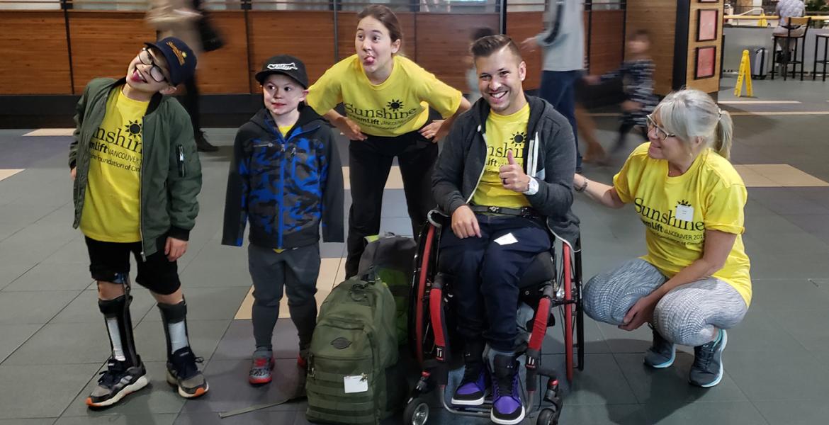 Group of various ages in matching yellow Sunshine t-shirts make funny faces of excitement in an airport lobby