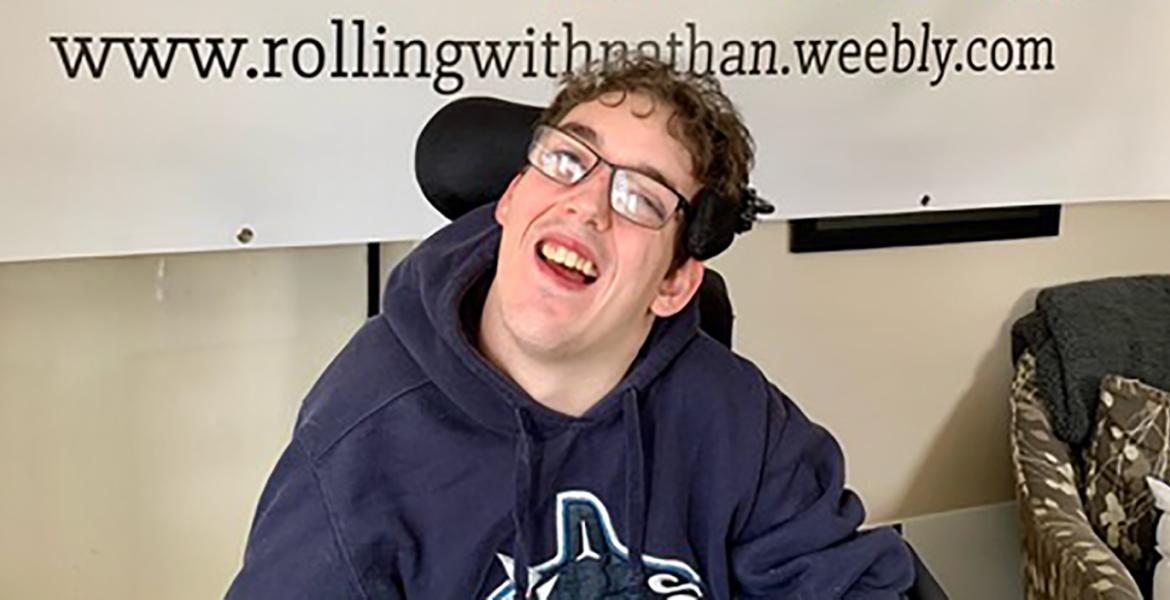 Nathan sourit dans son fauteuil roulant
