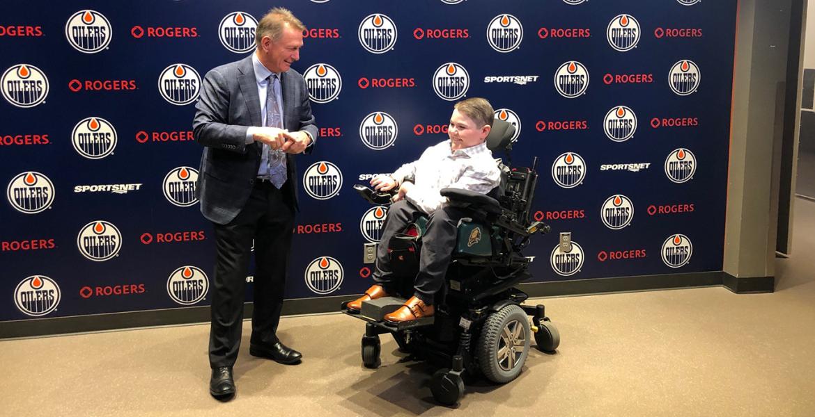 Owen and GM Ken Holland chatting in front of Edmonton Oilers logo backdrop
