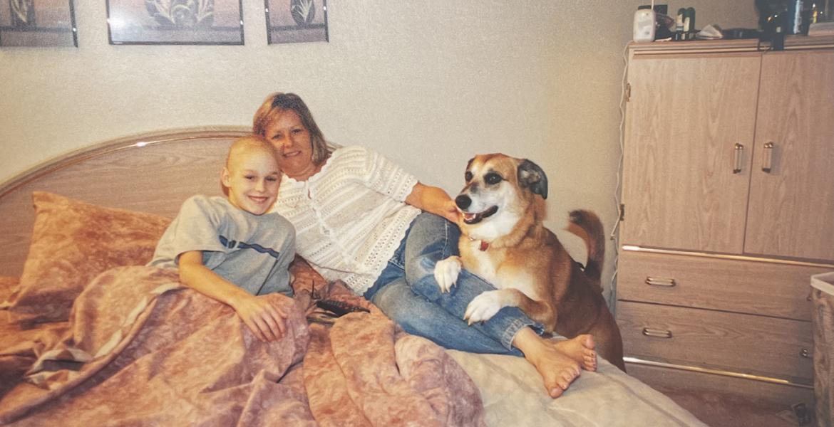 Ryan snuggled in bed next to mom and family dog 