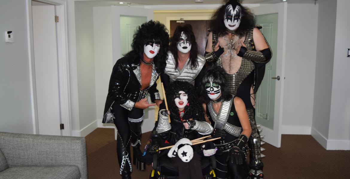 Victoria in full KISS cosplay poses with the entire band backstage