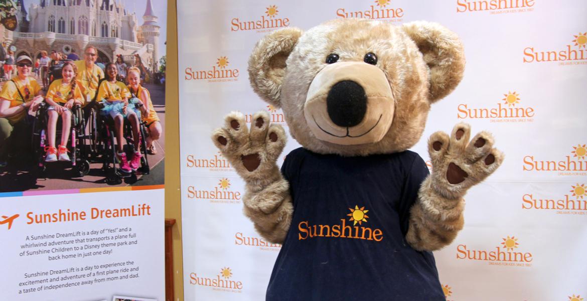 Sunshine Bear Mascot in front of Sunshine Foundation banners